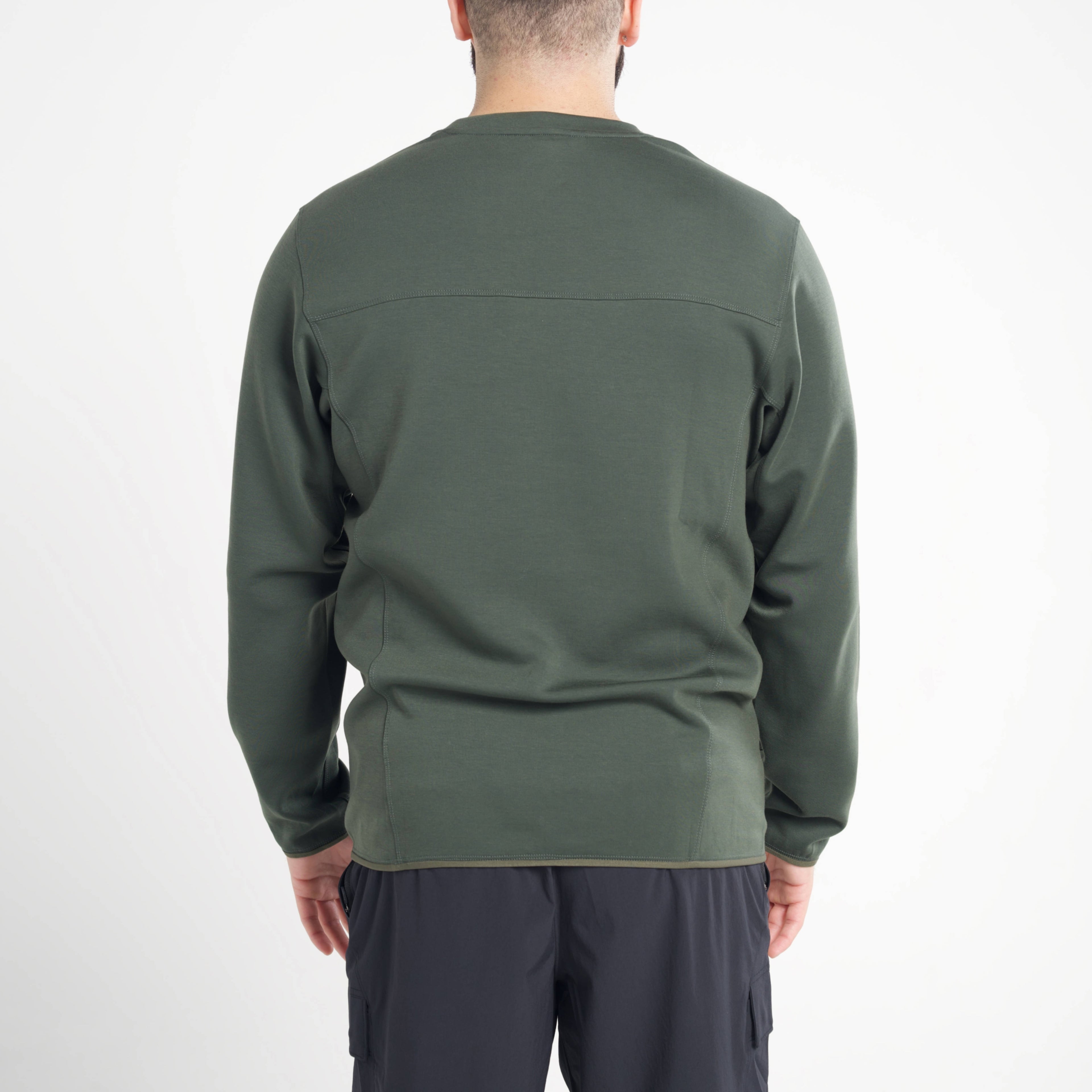 Person wearing a green long-sleeve shirt on a white background